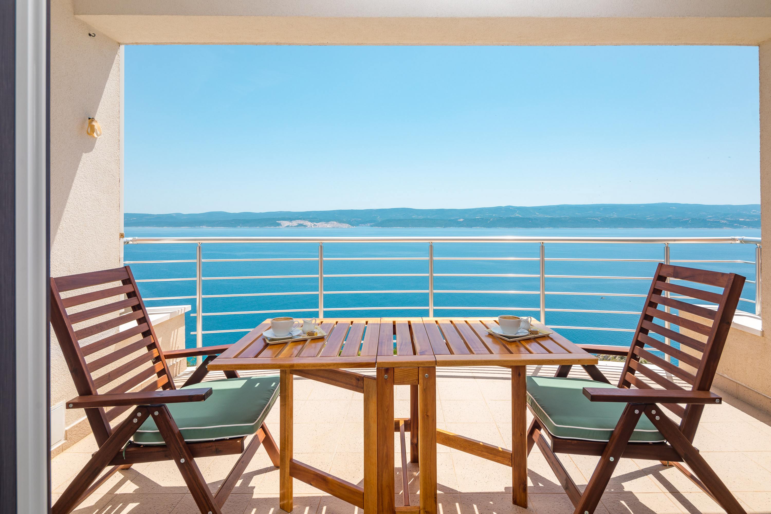 Terrace of Apartments Noah with two chairs and a table overlooking the Adriatic Sea and the island of Brač